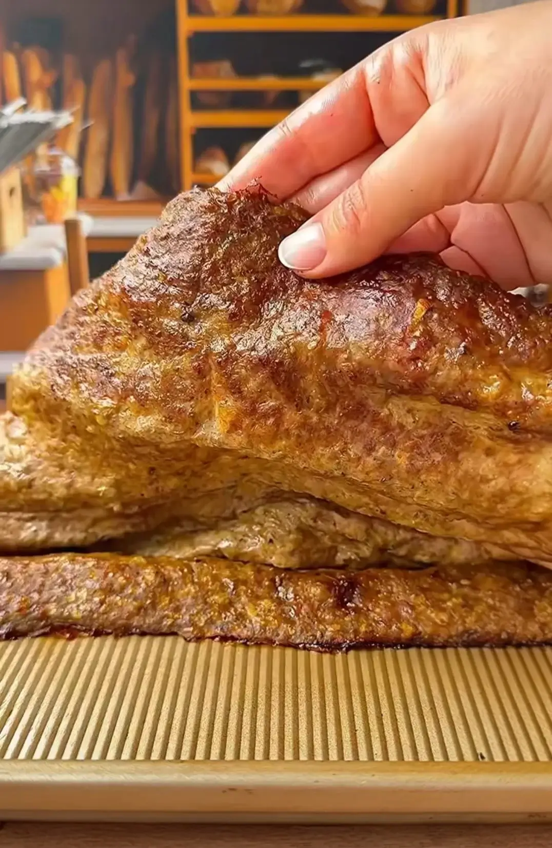 Hand lifting a freshly roasted doner kebab sheet to reveal its juicy, layered interior.