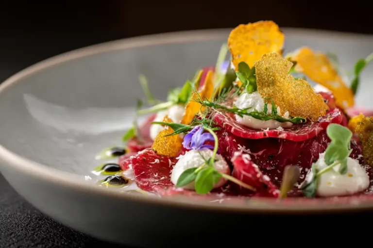 Beef Carpaccio Ribbon with Truffle Cream and Crispy Root Chips on marble counter.