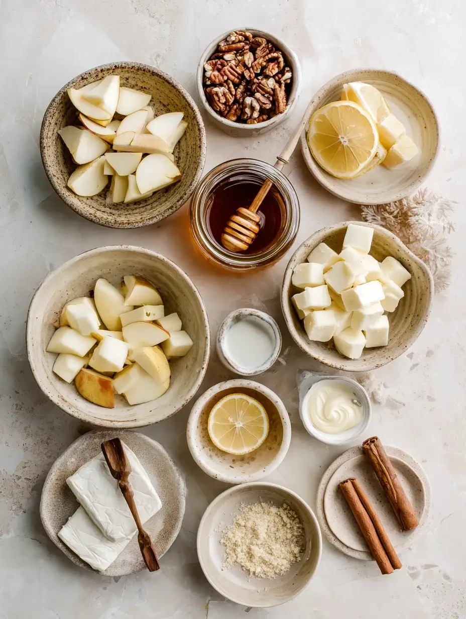 Flat lay of Brie, apples, honey, pecans, and cream on marble.