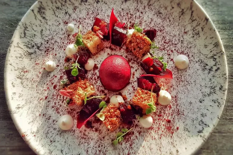 Beetroot sorbet plated with pickled beets, rye crumble, and horseradish cream on a ceramic plate